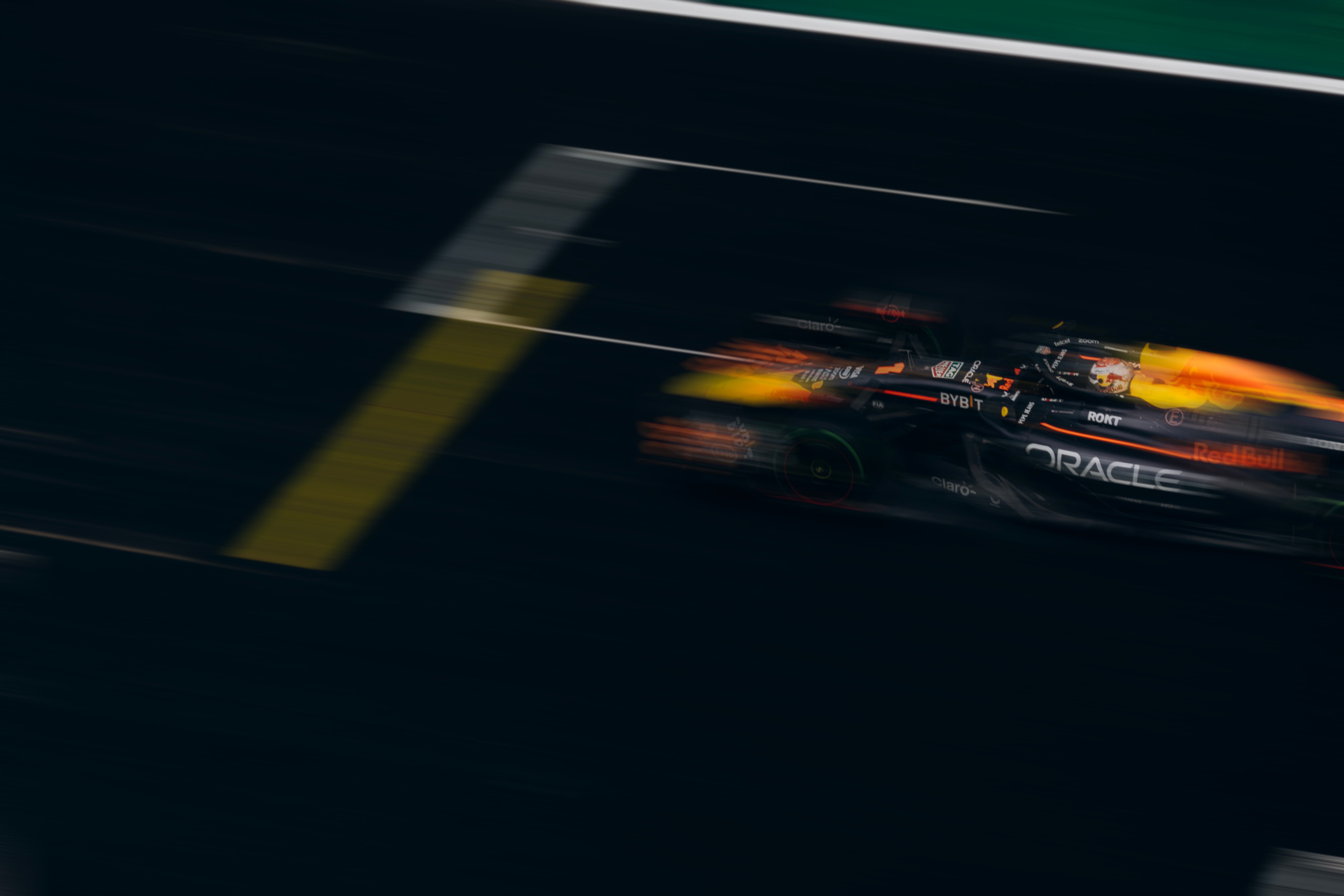 Formula 1 car at speed, motion-blurred against a dark track